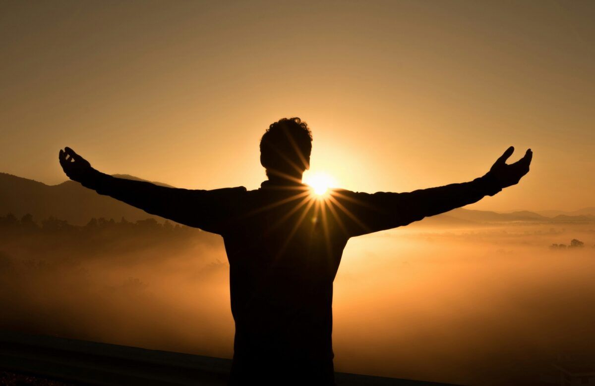 a man standing with open arm during sunset and relaxing